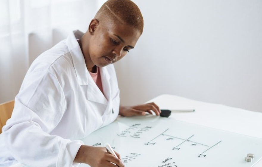 Person writing on a whiteboard desk.