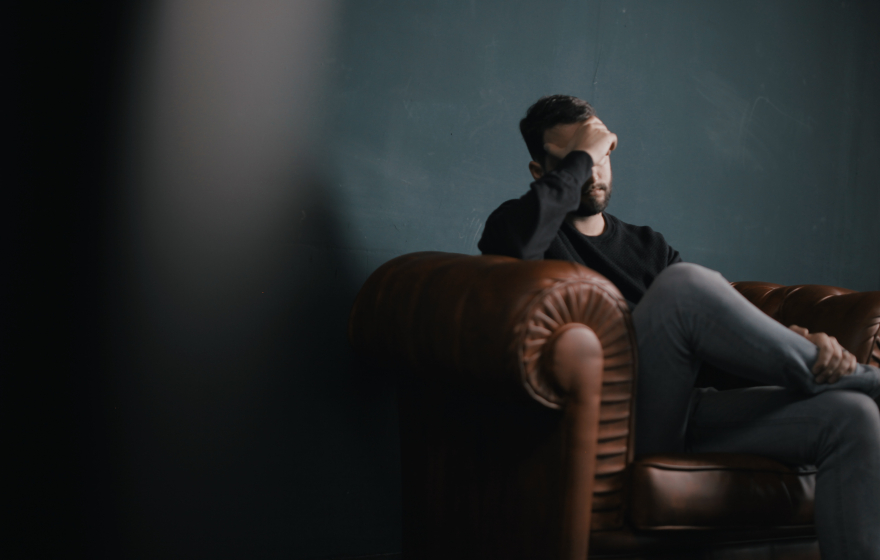 man sitting with hand on head in distress.