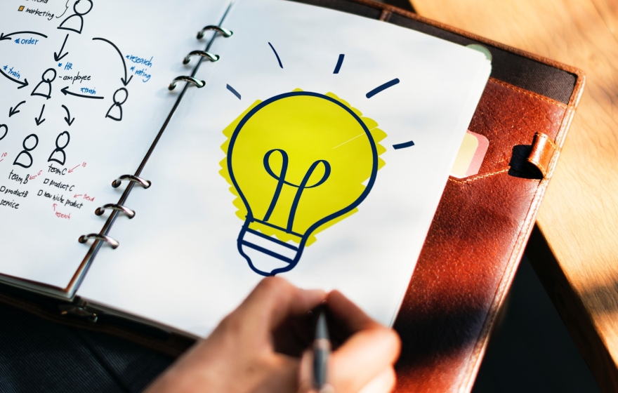notebook on a person's lap with a light bulb