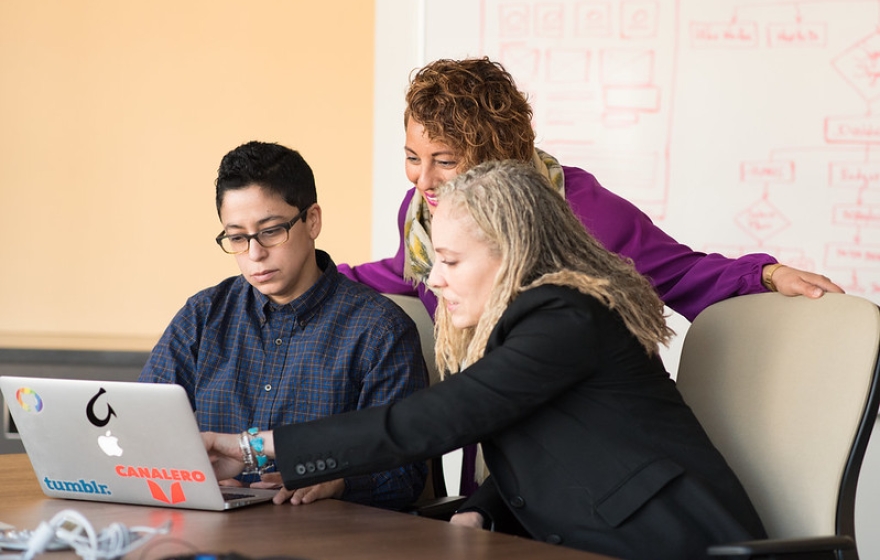 three people gather around a computer