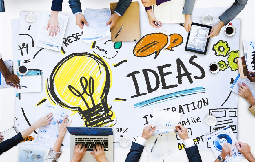 top view of a messy desk with people around it writing ideas down