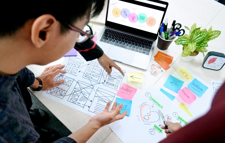 student at a desk with a laptop, notes, and sticky notes strewn about