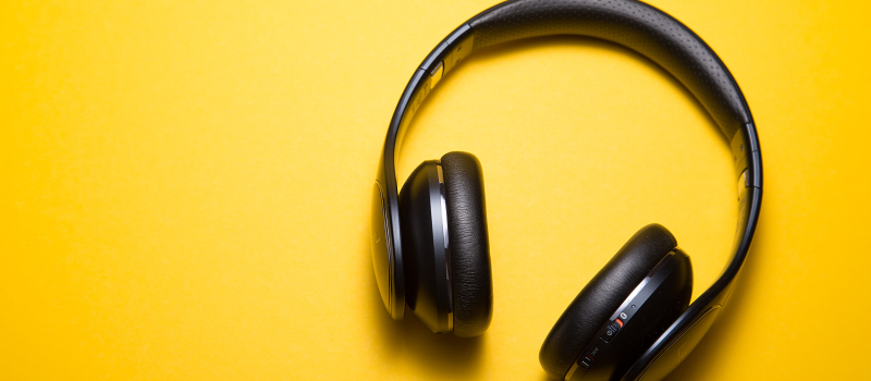 Black headphones on a plain yellow background.