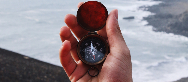 Holding a compass in front of an ocean background.