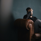 man sitting with hand on head in distress.