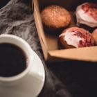 A cup of black coffee and a box of donuts.