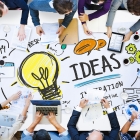 top view of a messy desk with people around it writing ideas down