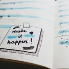 planning notebook with a sticky note saying Make it Happen!