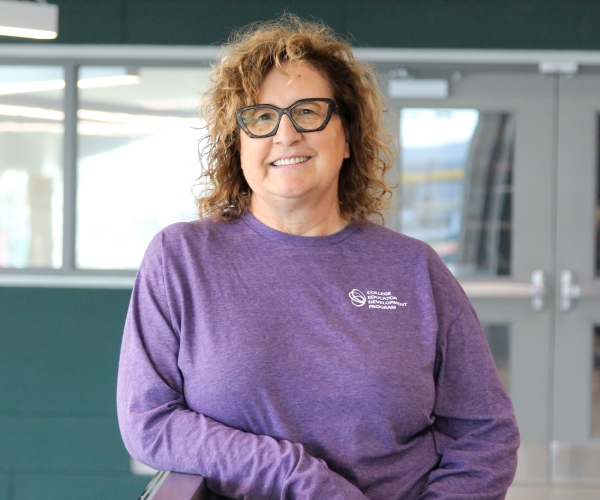 Kathryn wears a purple CEDP shirt and smiles toward the camera